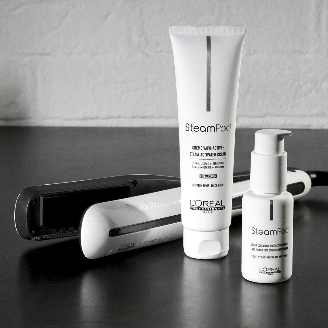 Haarstylingtools en -producten op een donkere ondergrond. Inclusief een stijltang, stylingcrème en serum.