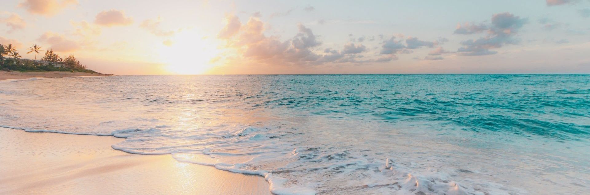 the waves are breaking on the beach at sunset .