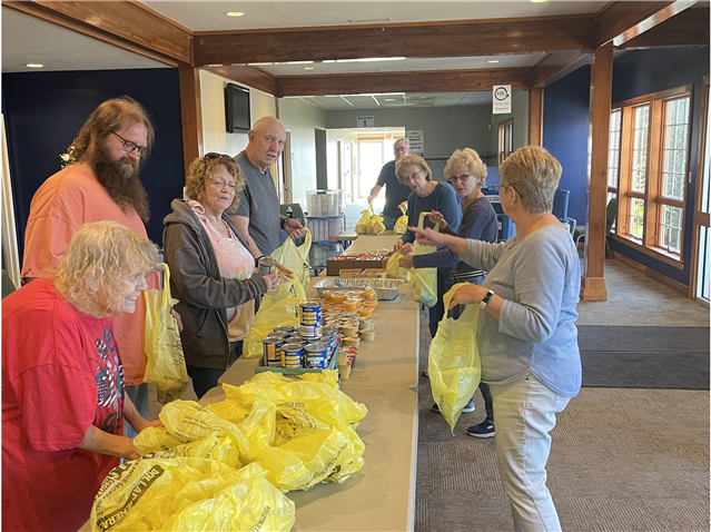 A group of church members are standing around a table filling bags of food.