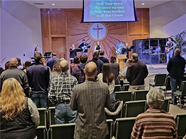 A group of people are sitting in a church participating in worship.
