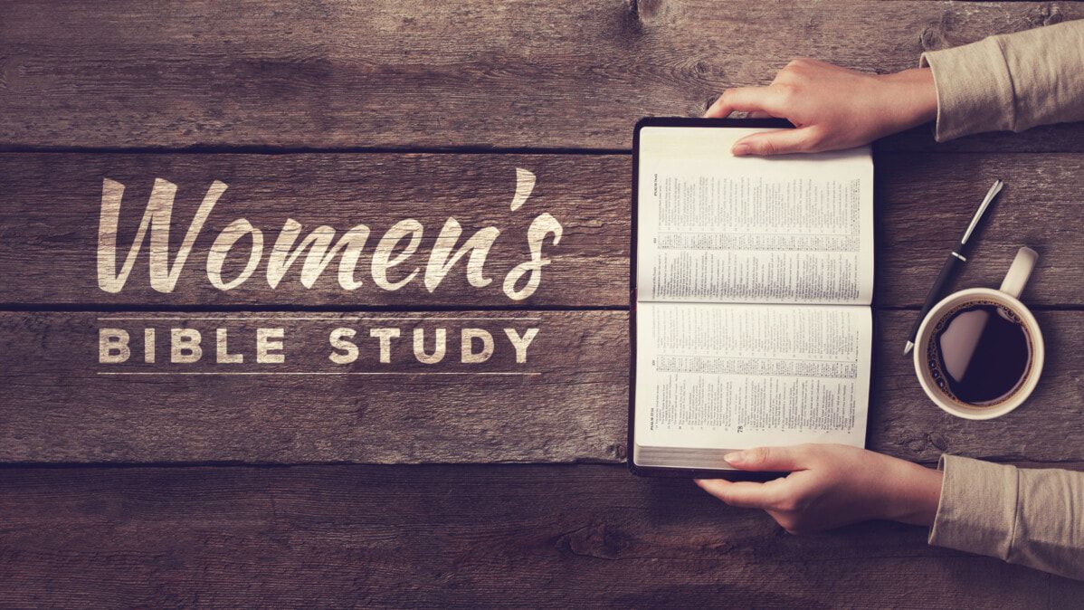 A woman is holding a bible and a cup of coffee on a wooden table.