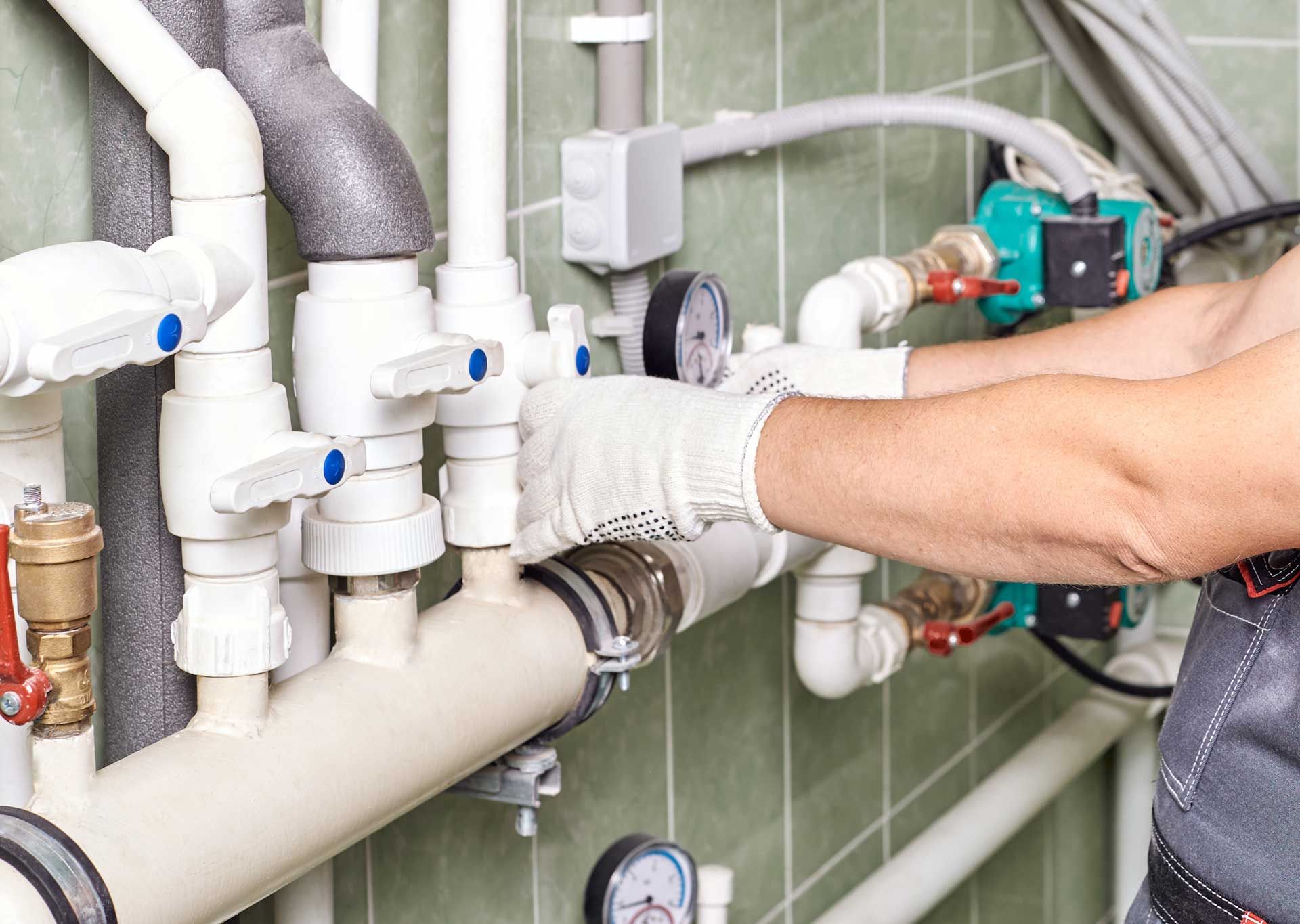 Technician repairing industrial piping with gloves and tools in a plant
