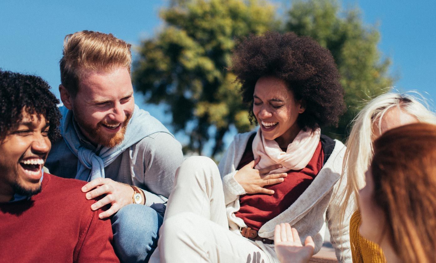 two men and two women who are friends laughing and enjoying themselves in a park