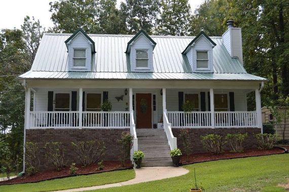 A white house with a metal roof and a porch