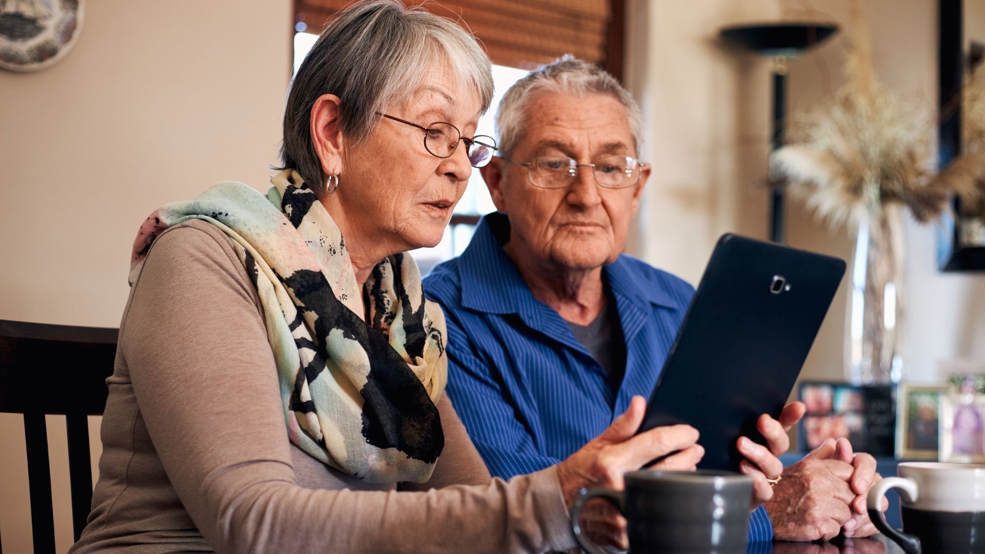 Older couple looking at tablet together indoors.