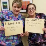 Two women holding signs saying