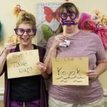 Two women posing with paper signs: