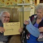Elderly couple holding signs. Man's sign reads