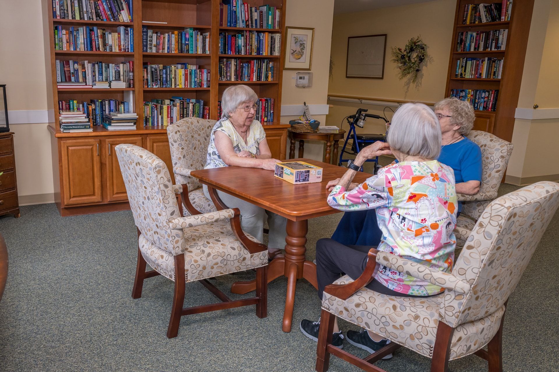 Four women seated around a table playing a game in a library.