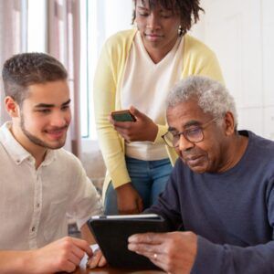 Three people looking at a tablet together, one holding a phone.