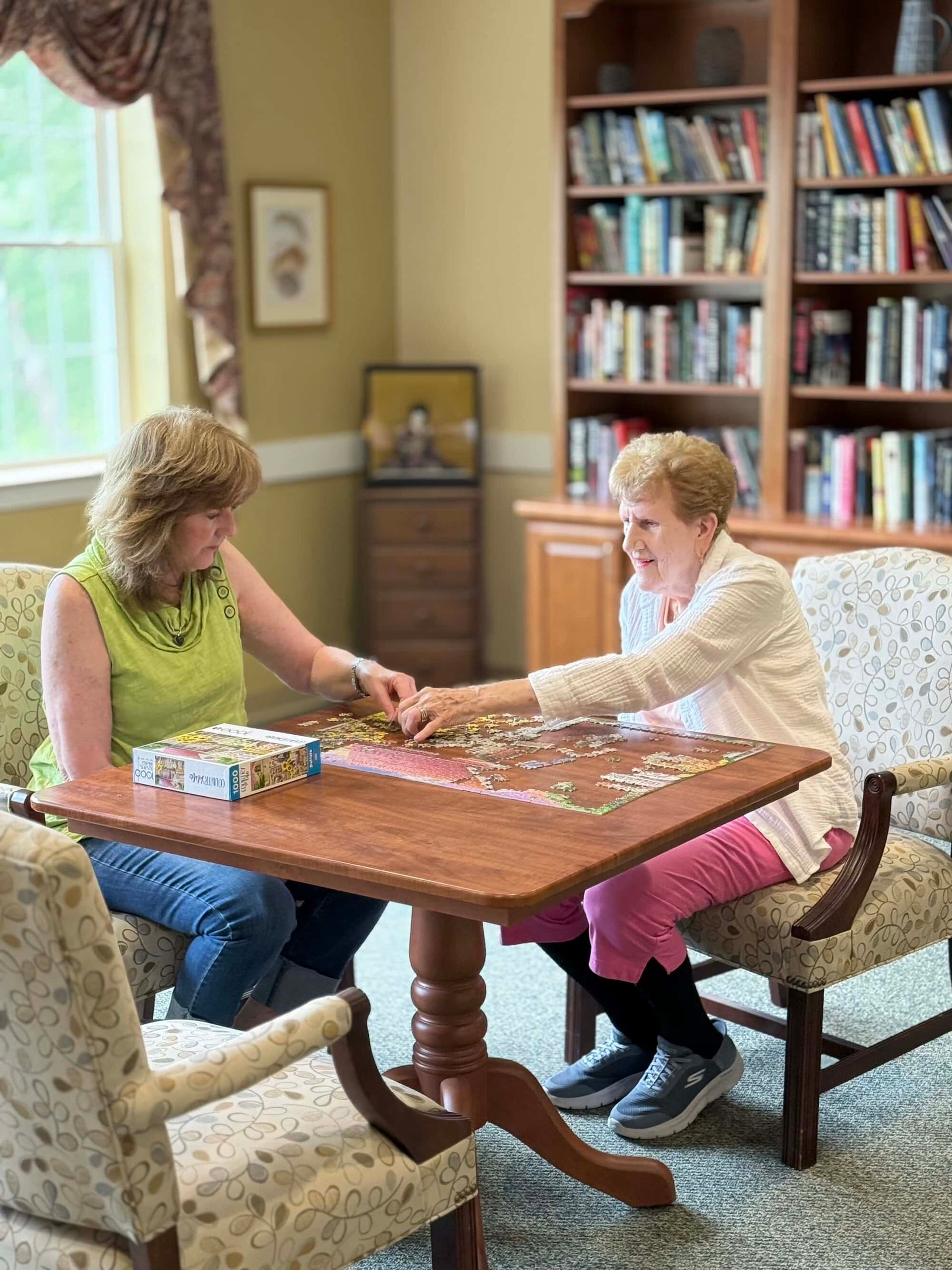 Two people working on a jigsaw puzzle at a table in a library.
