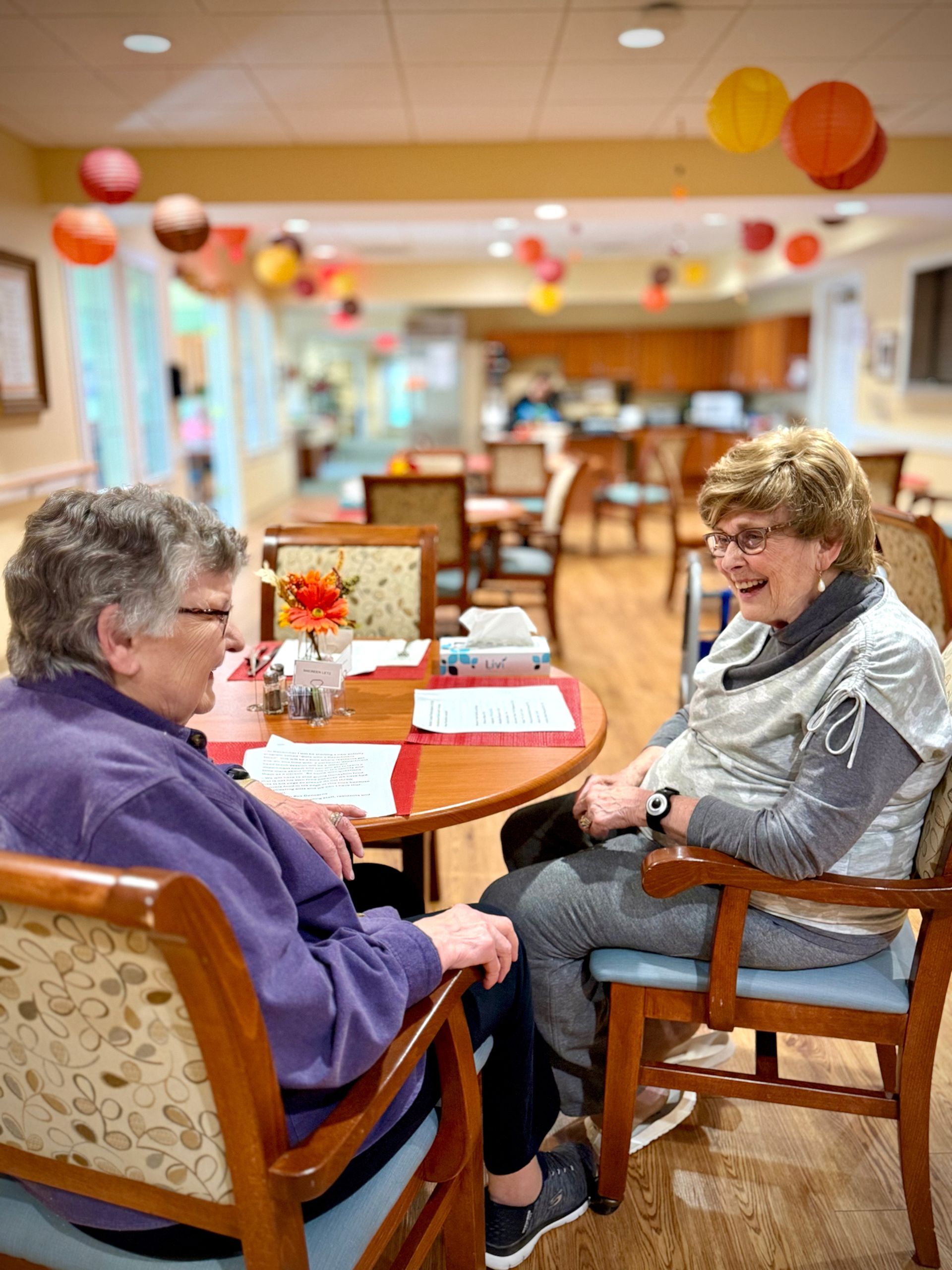 Seniors in a bright studio doing seated arm stretches during a group exercise class