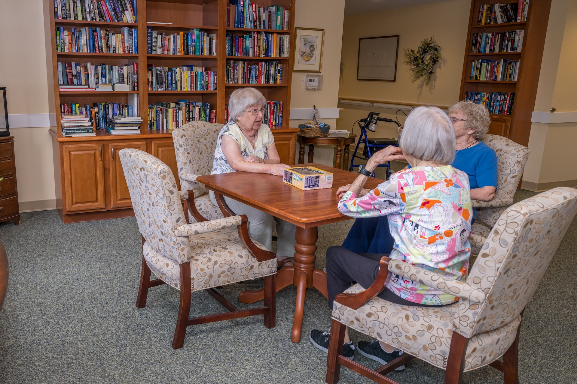 Three women seated around a table playing a game in a library.