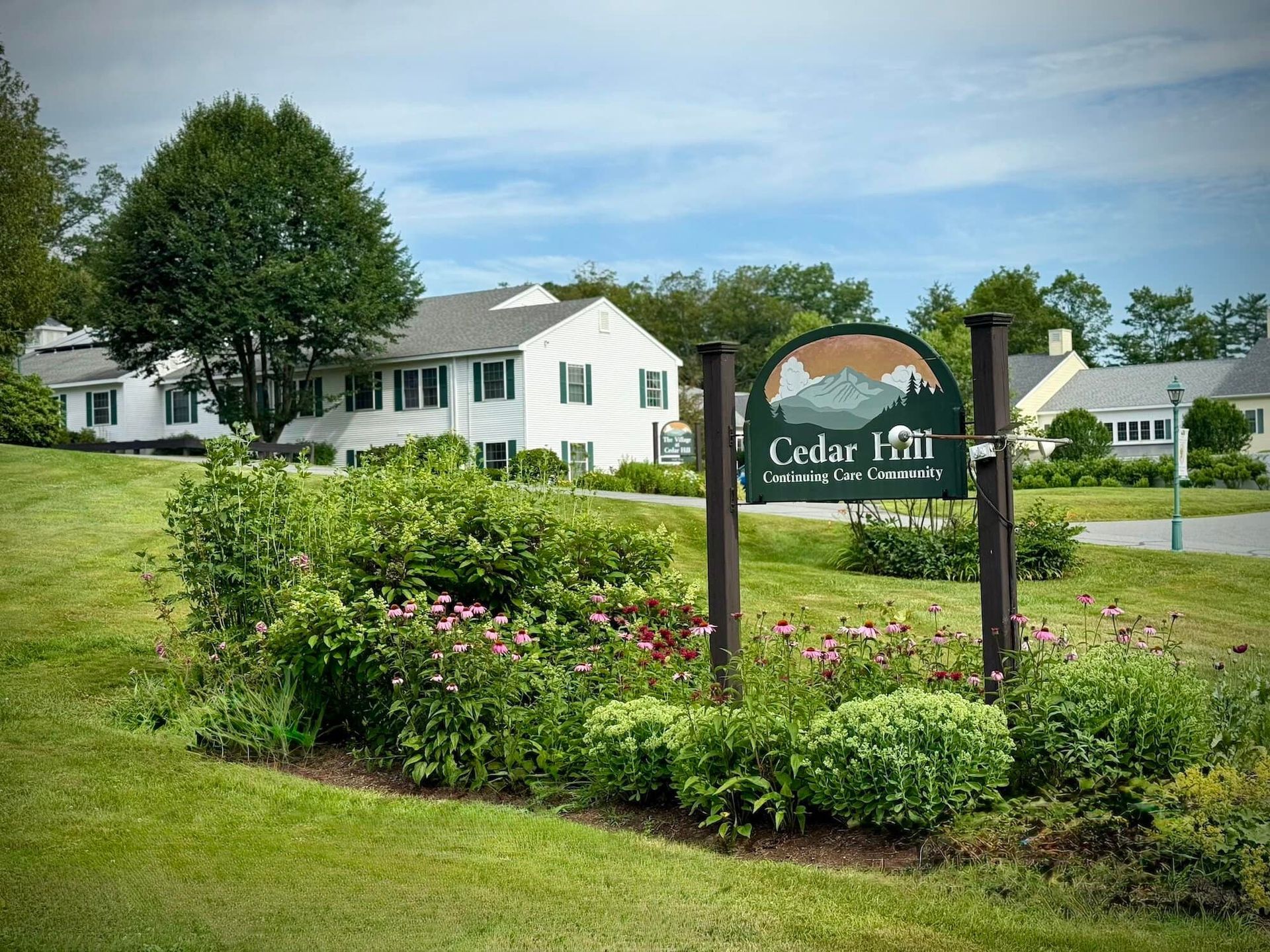 Cedar Hill community sign with white houses and a flower garden.
