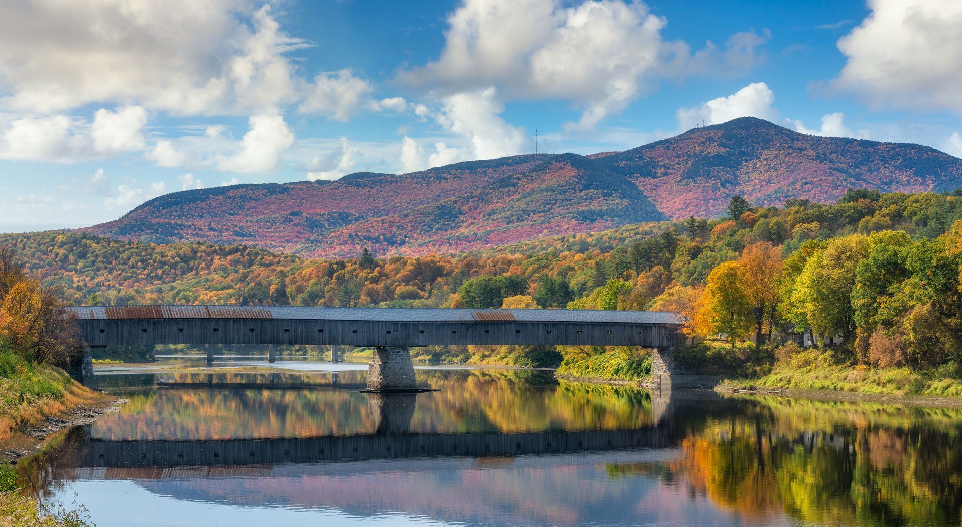 A bridge over a river with mountains in the background.