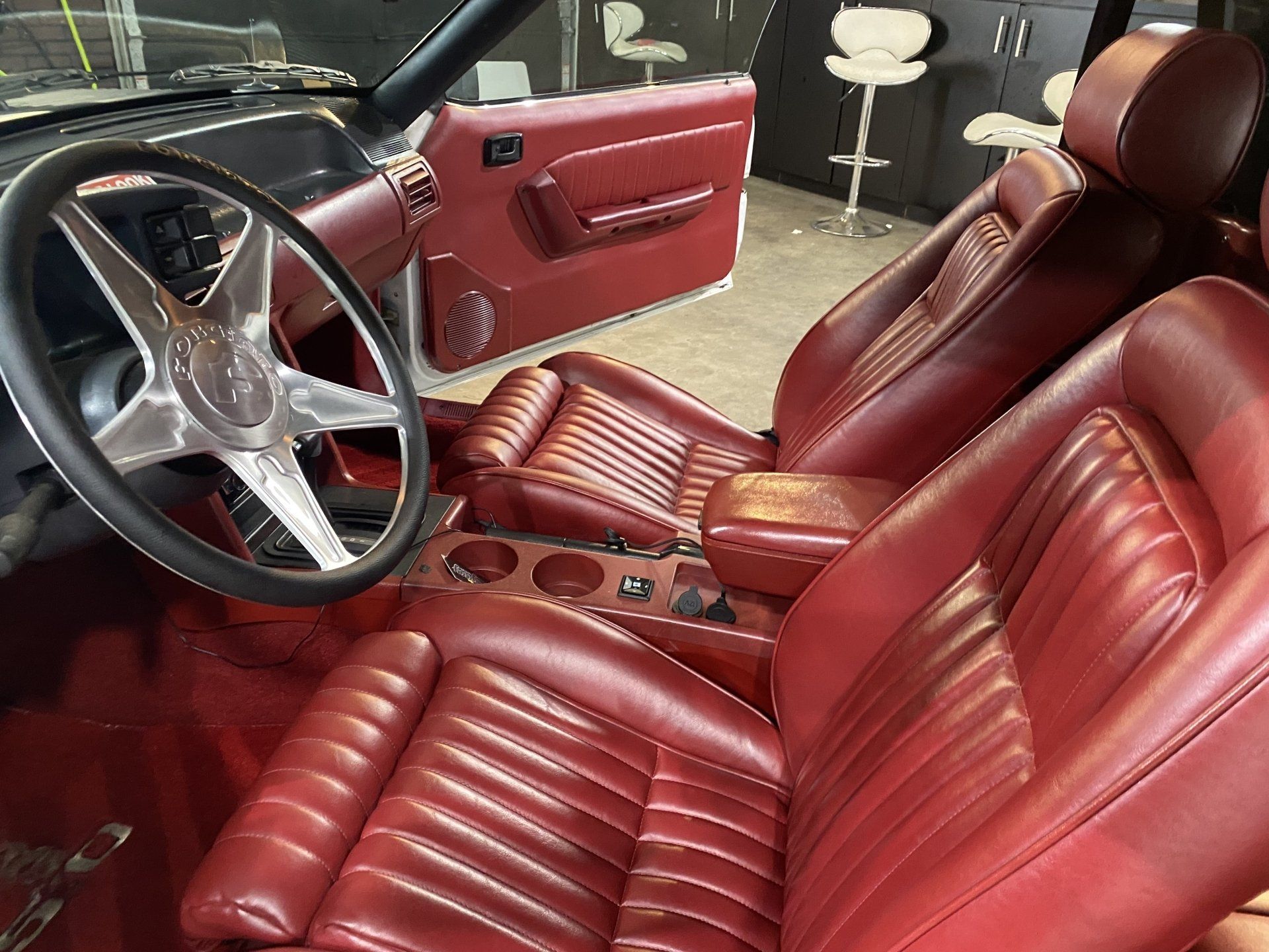 Red leather car interior with bucket seats, steering wheel, and matching door panel.