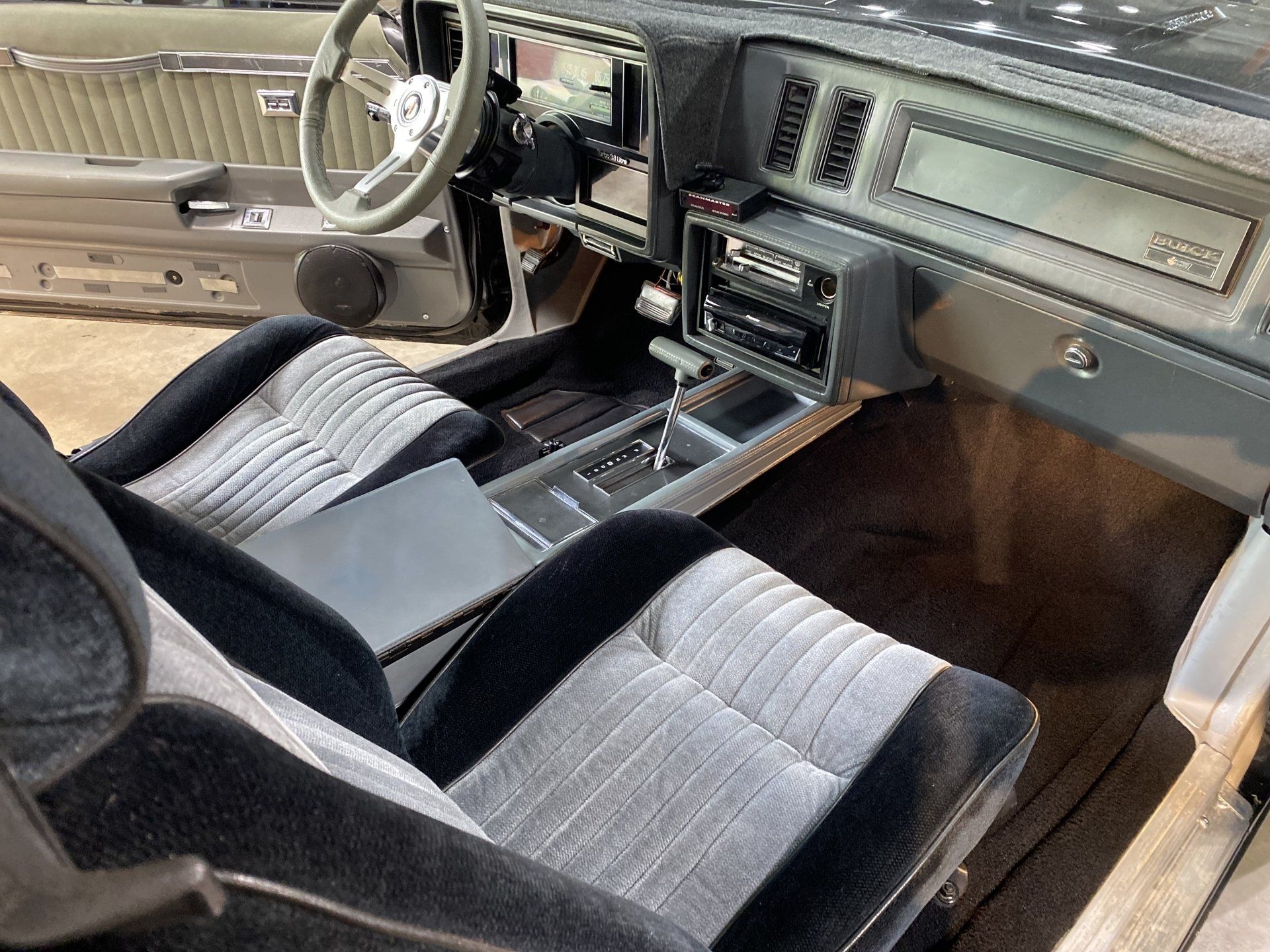 Vintage car interior with gray bench seats, steering wheel, and dashboard with wood trim