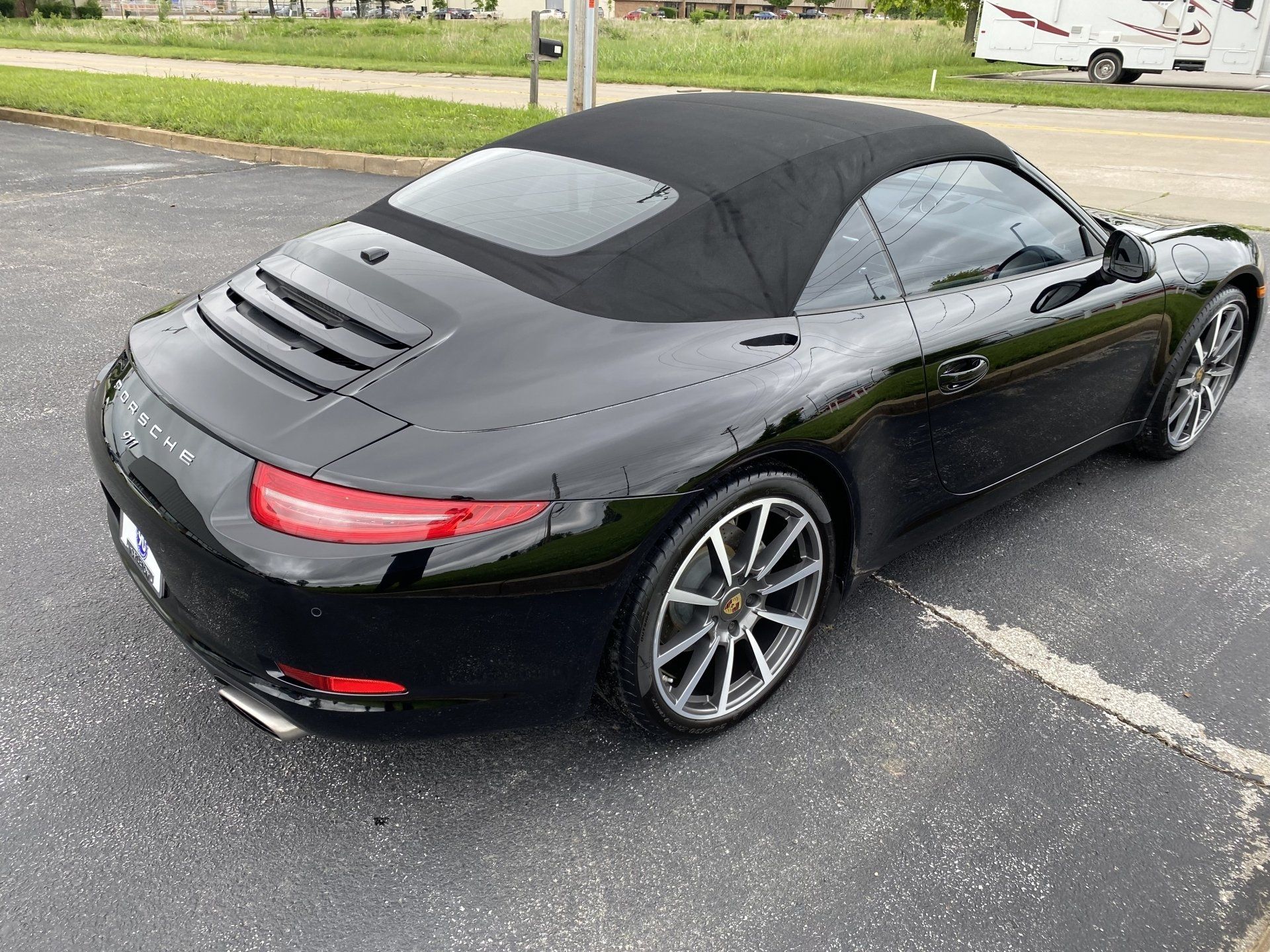 Black convertible sports car parked on asphalt in a lot, rear three-quarter view