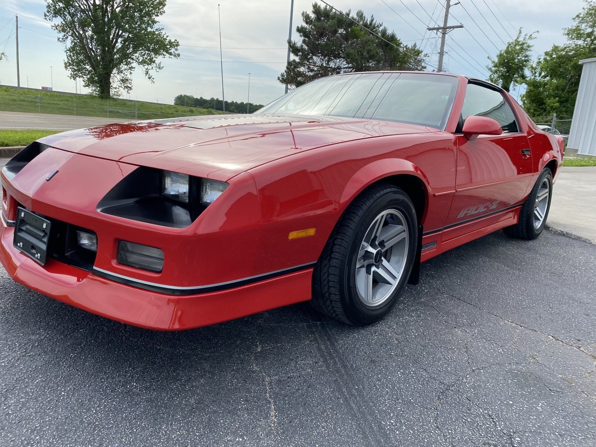 Red sports car parked on a wet road under a cloudy sky