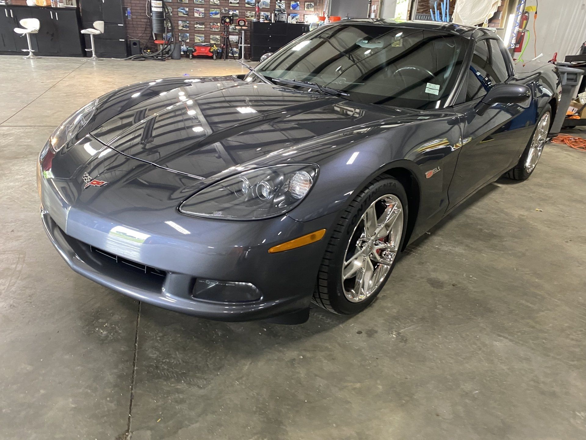 Gray sports car parked indoors in a garage, front-left view.
