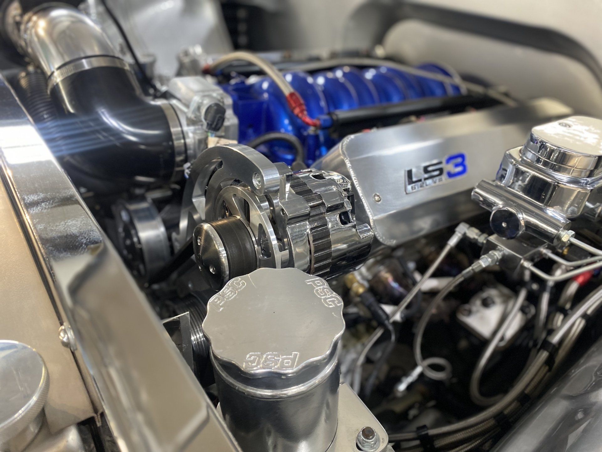 Polished LS3 car engine bay with chrome intake, blue supercharger, and visible performance components