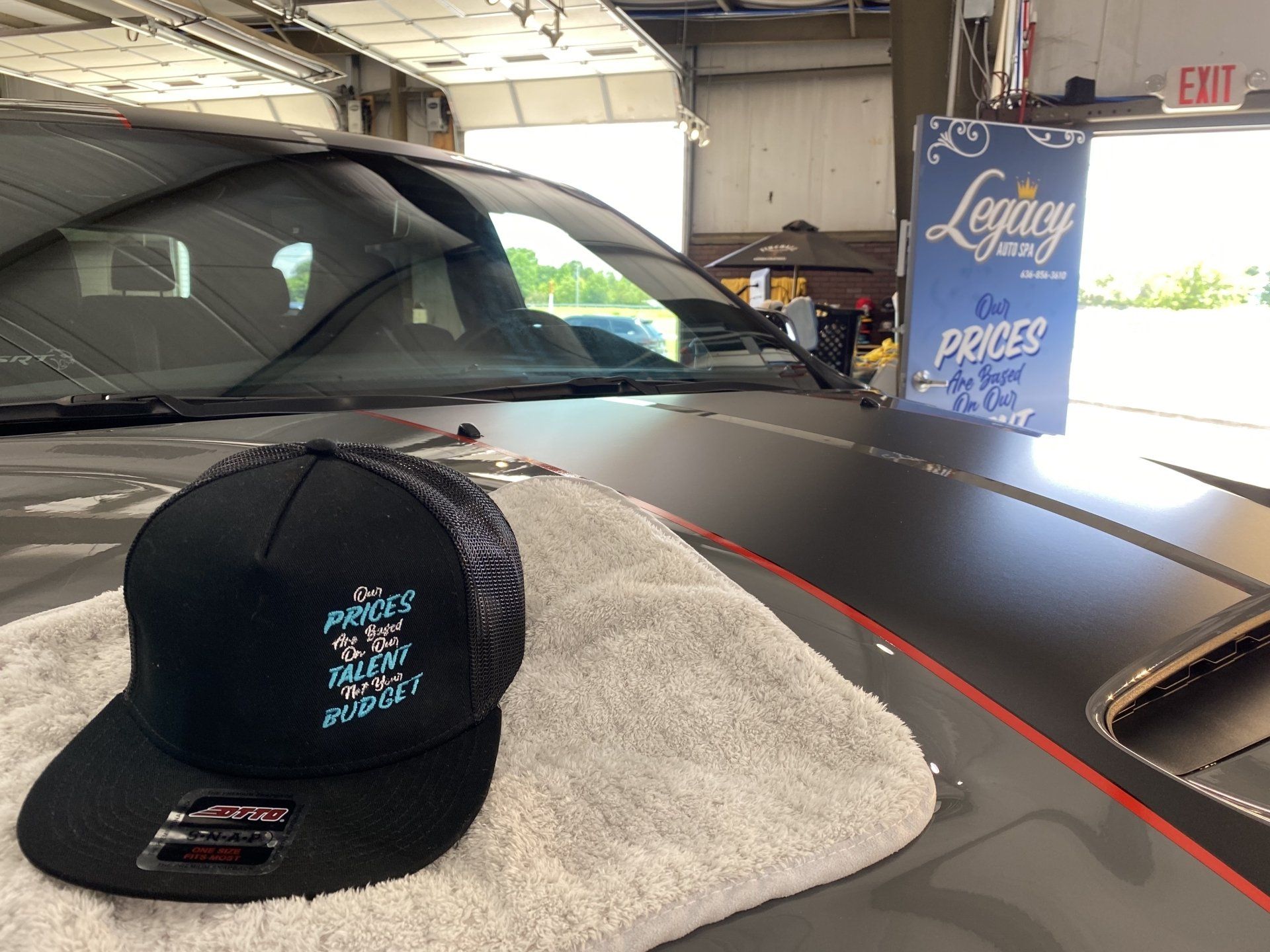 Black cap on a car hood with a display sign in a garage showroom
