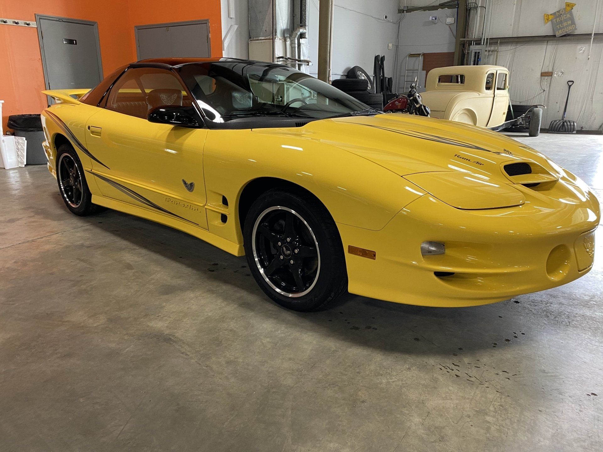 Yellow sports car parked indoors in a garage, angled front-left view.