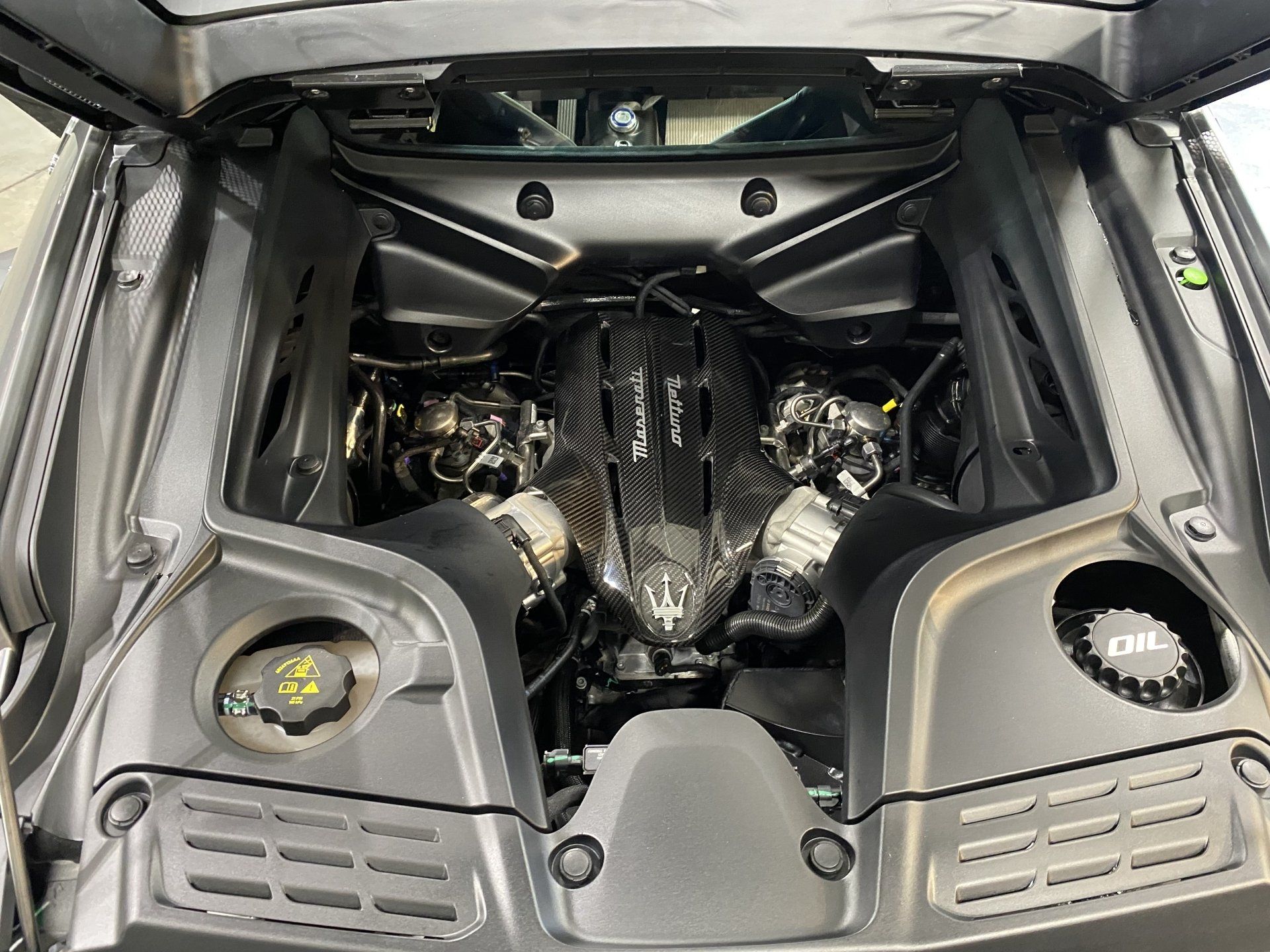 Car engine bay with a central black engine cover and two large air intakes under the open hood