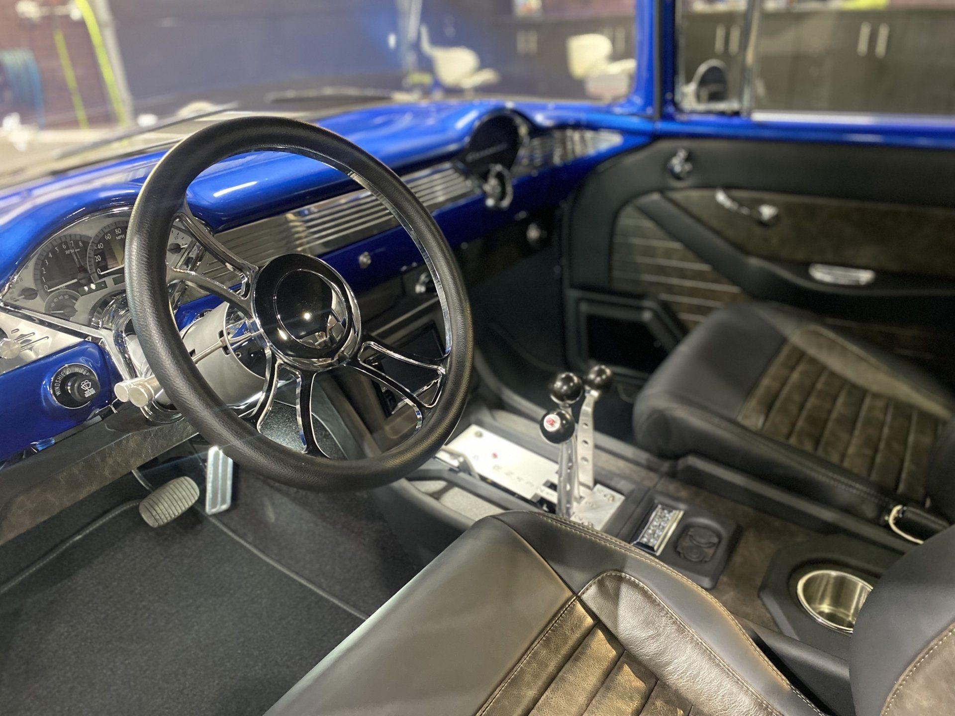 Blue vintage car interior with black seats, steering wheel, and manual gear shift visible