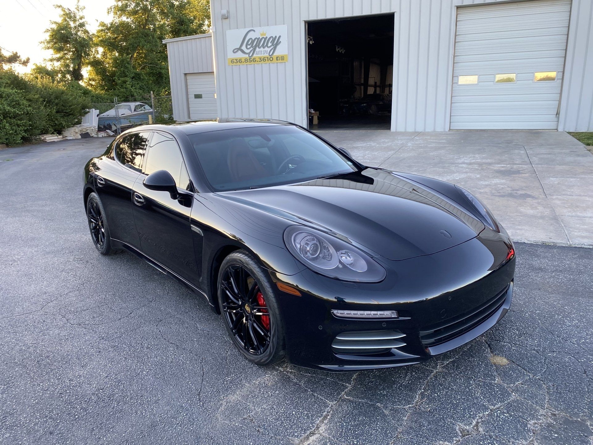 Black Porsche sports car parked outside a warehouse garage