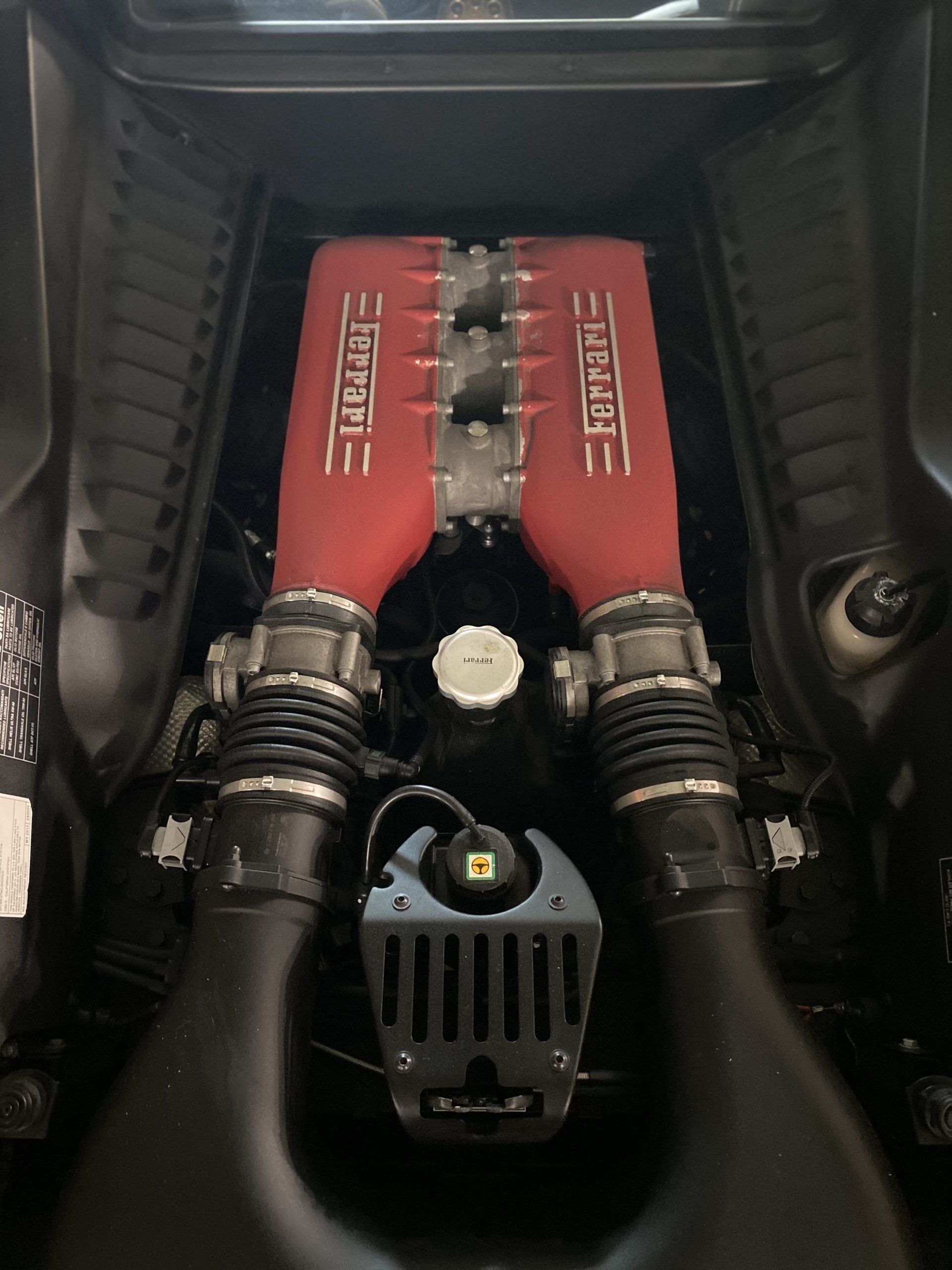 Red engine bay with twin intake pipes and a Ferrari engine cover visible under the hood.