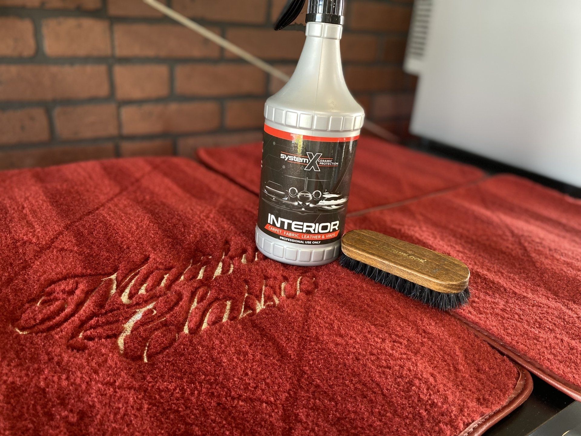 Bottle of Super Glue on a red towel with a wooden brush, against a brick wall.