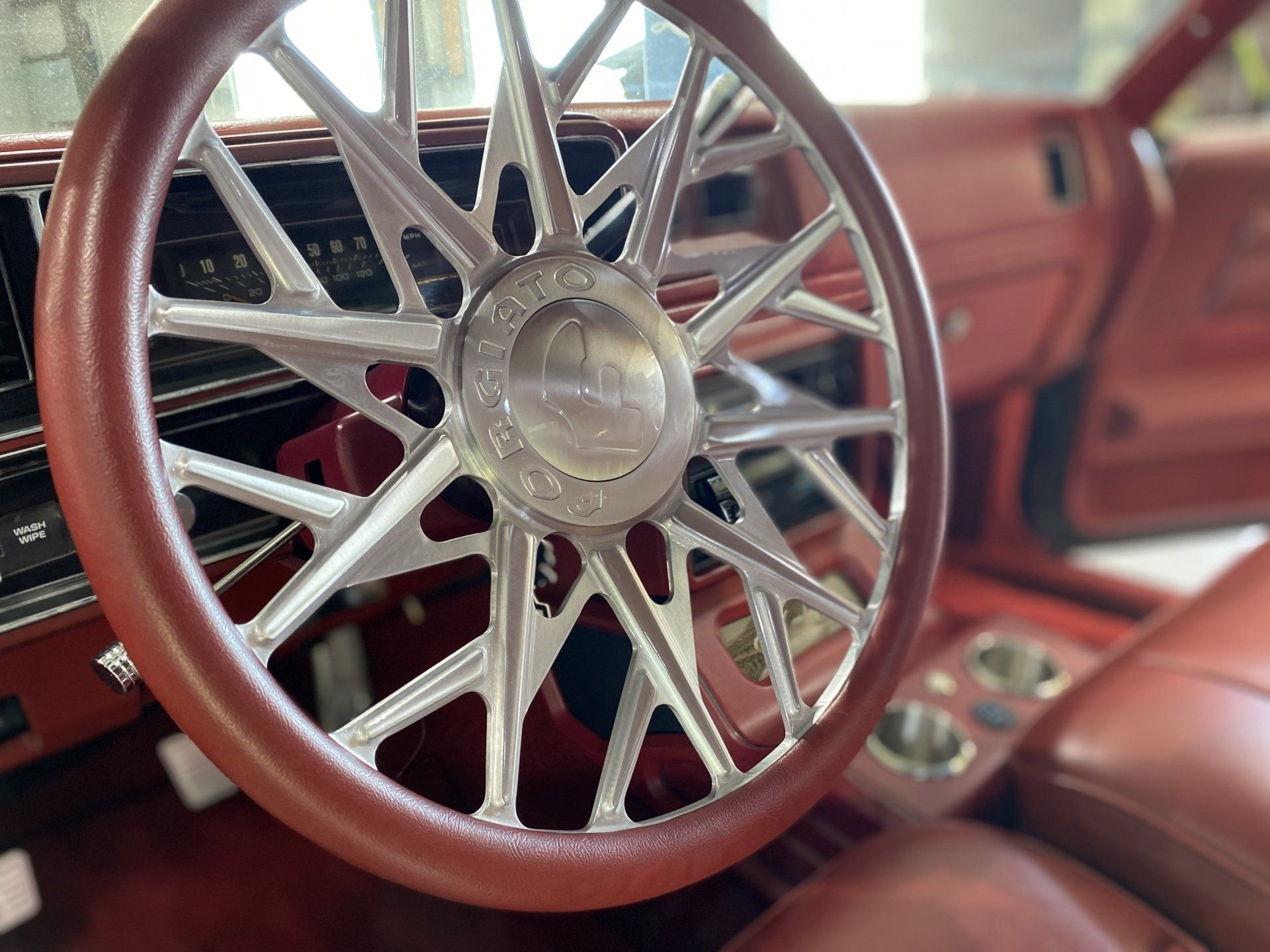Custom car interior with a wood-and-chrome steering wheel and red leather seats
