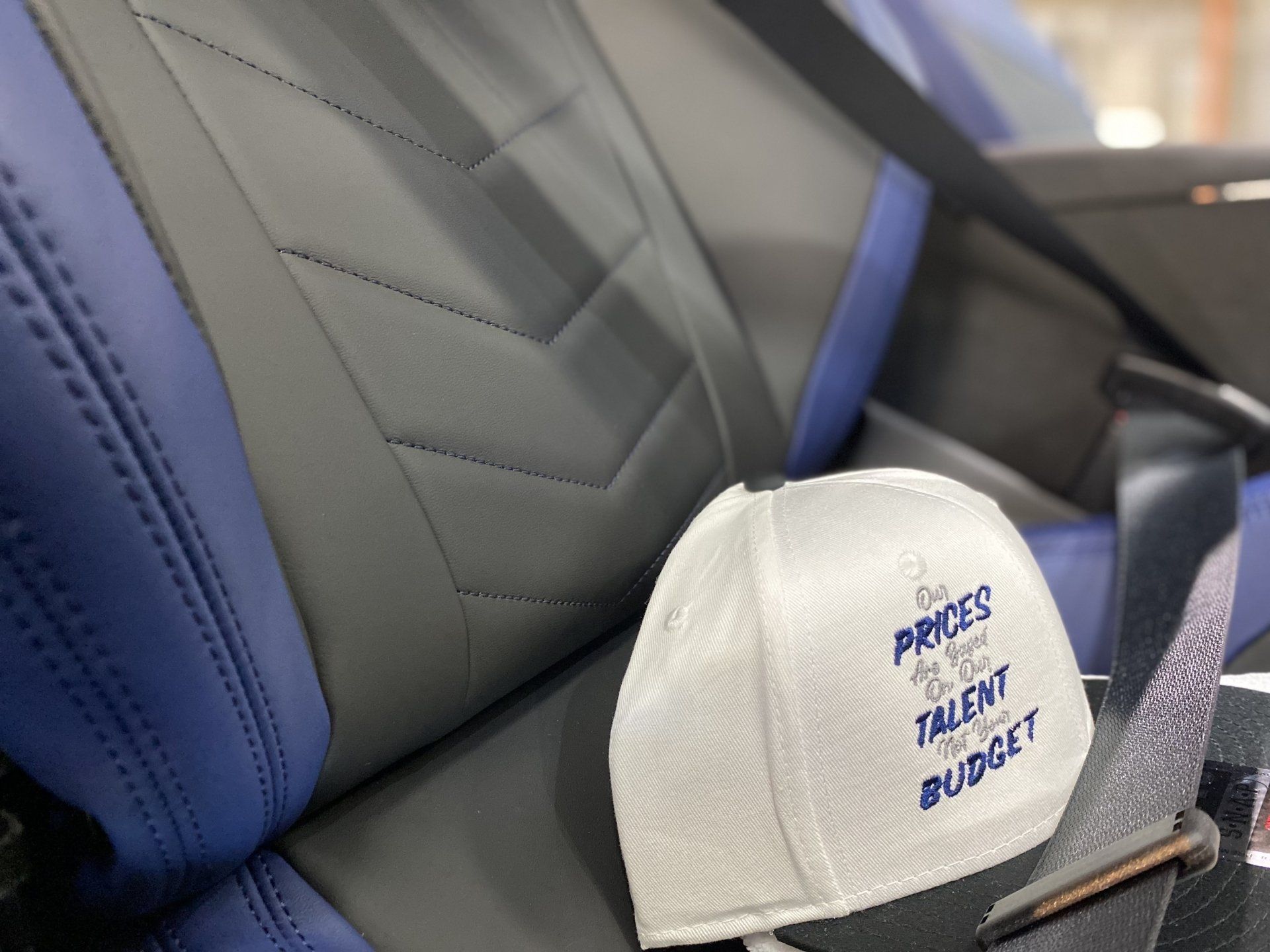 White cap with blue logo on gray-and-blue car seat interior
