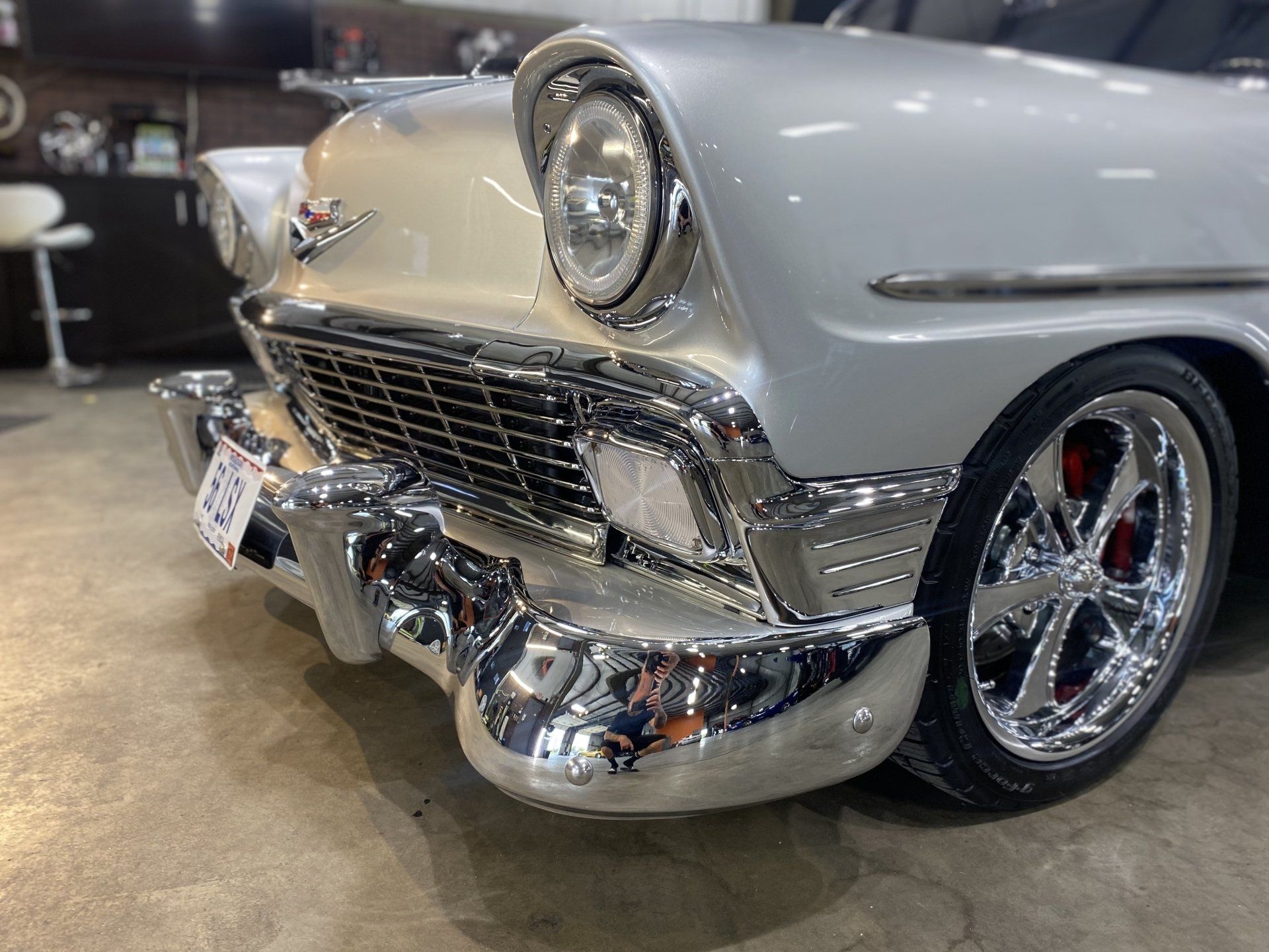 Classic white vintage car front end with chrome bumper and grille at an indoor show