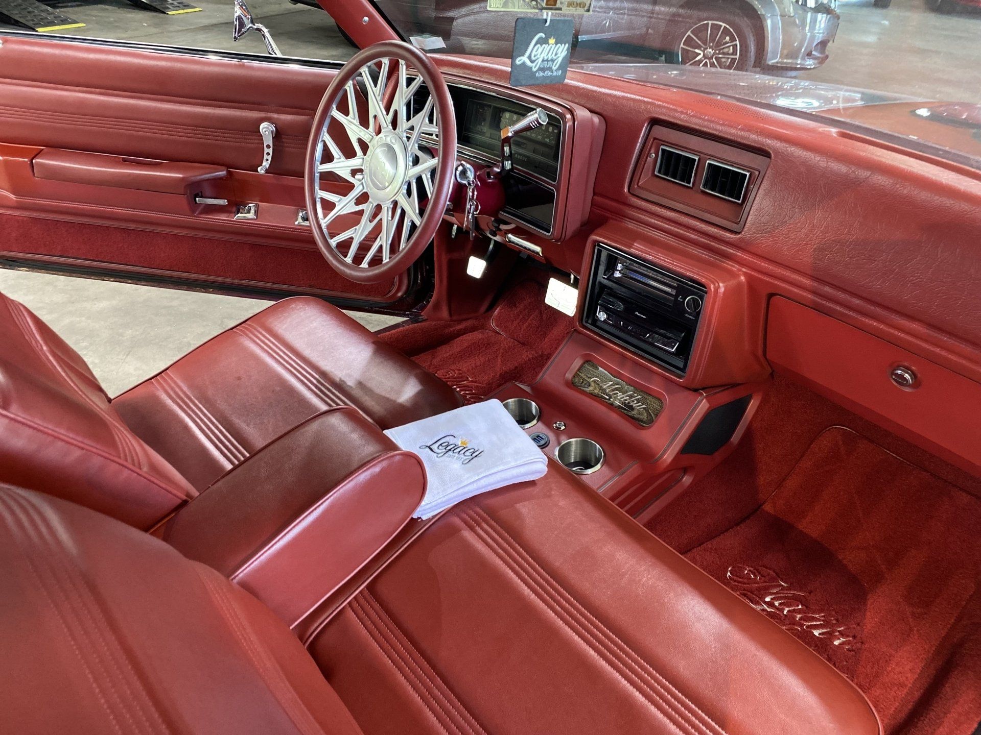 Red leather car interior with custom steering wheel, dashboard, and center console.