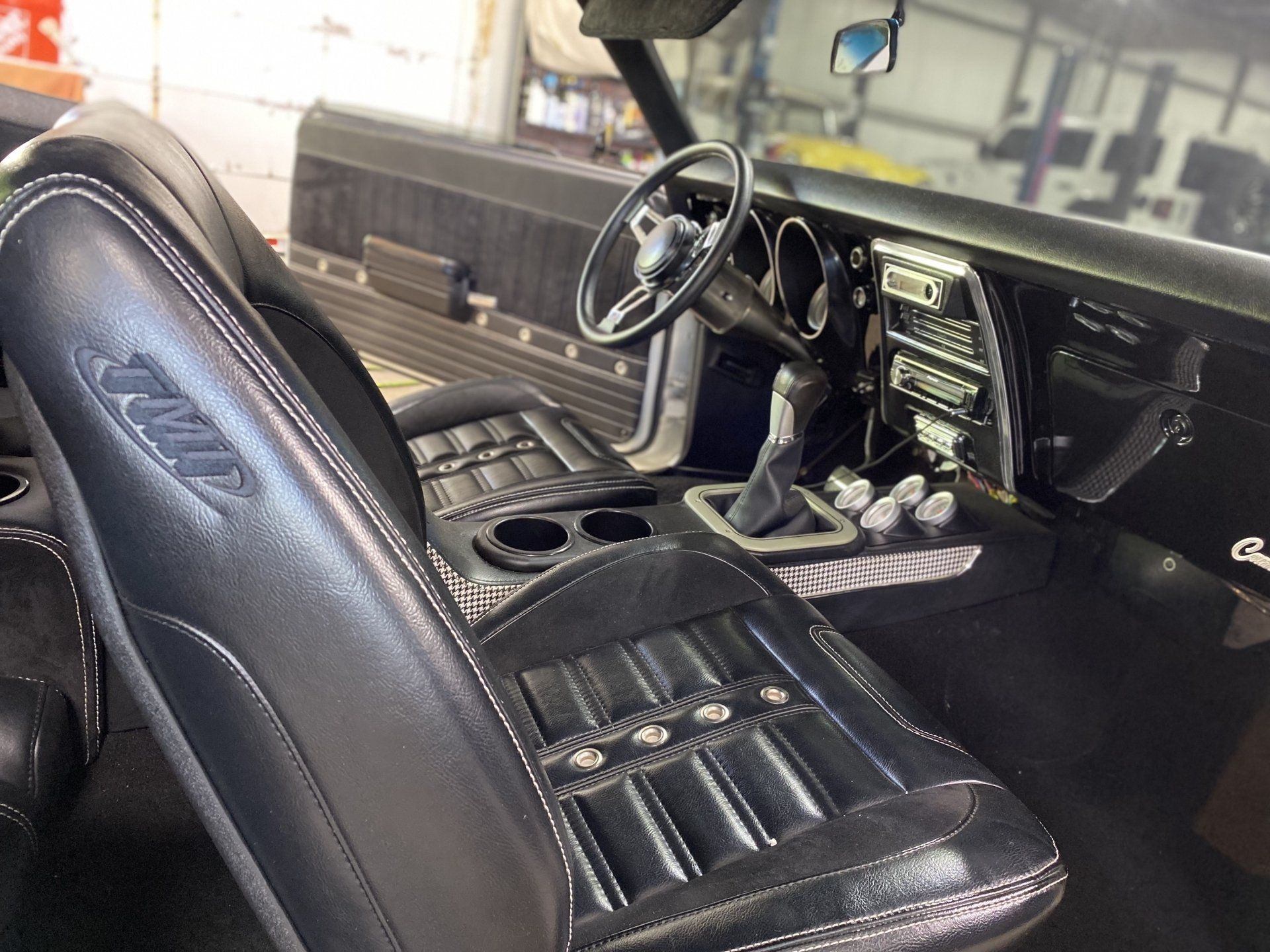 Black leather truck interior with bucket seats, steering wheel, and center console viewed from the front seat