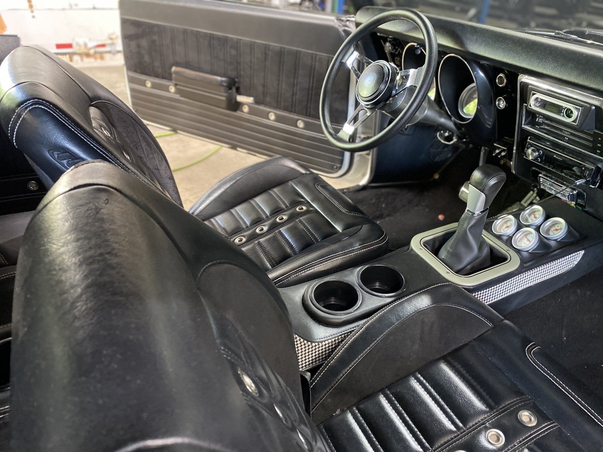 Classic sports car interior with black leather seats, dashboard gauges, and center console controls