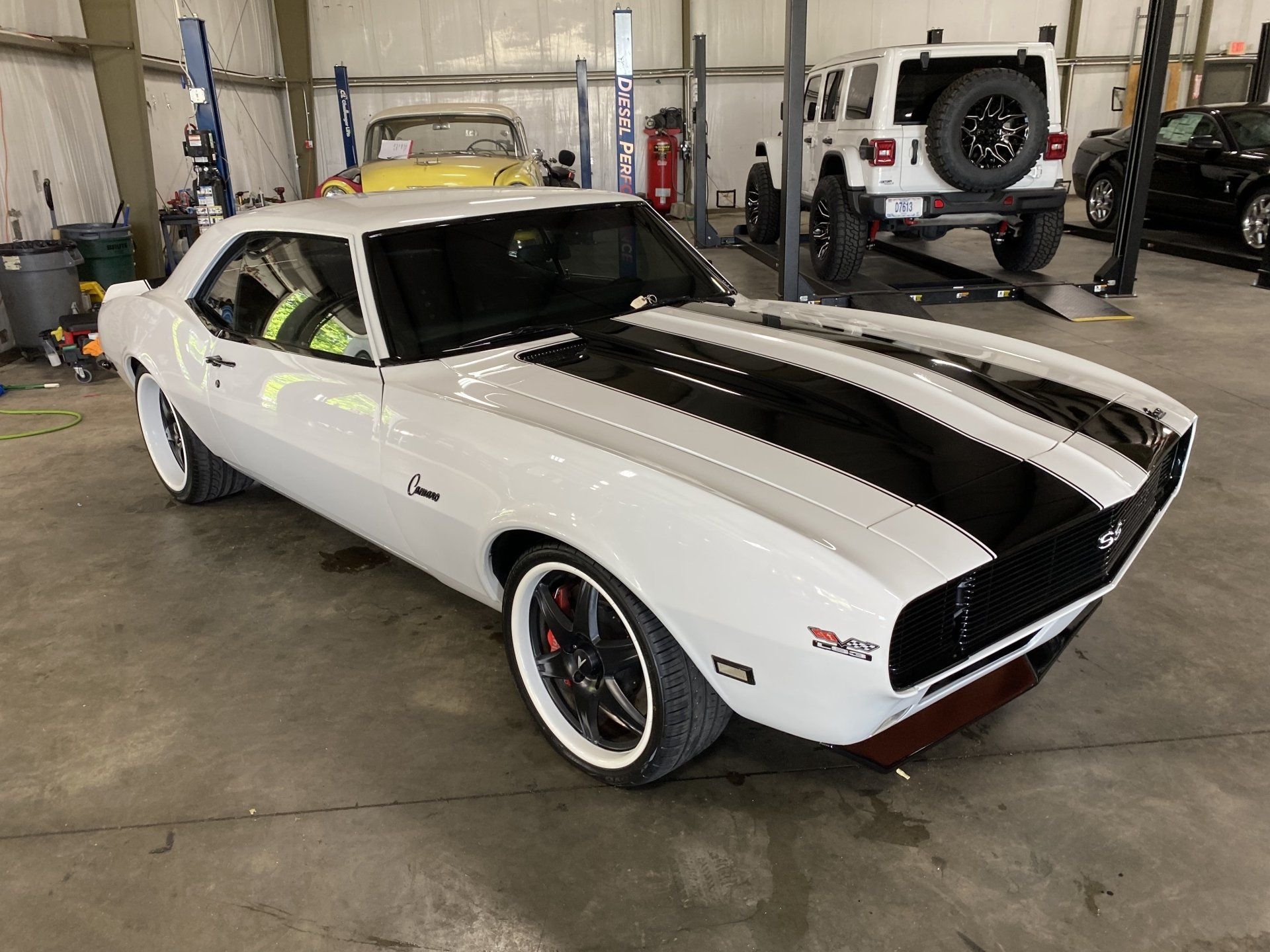 White classic muscle car with black racing stripes parked in a garage
