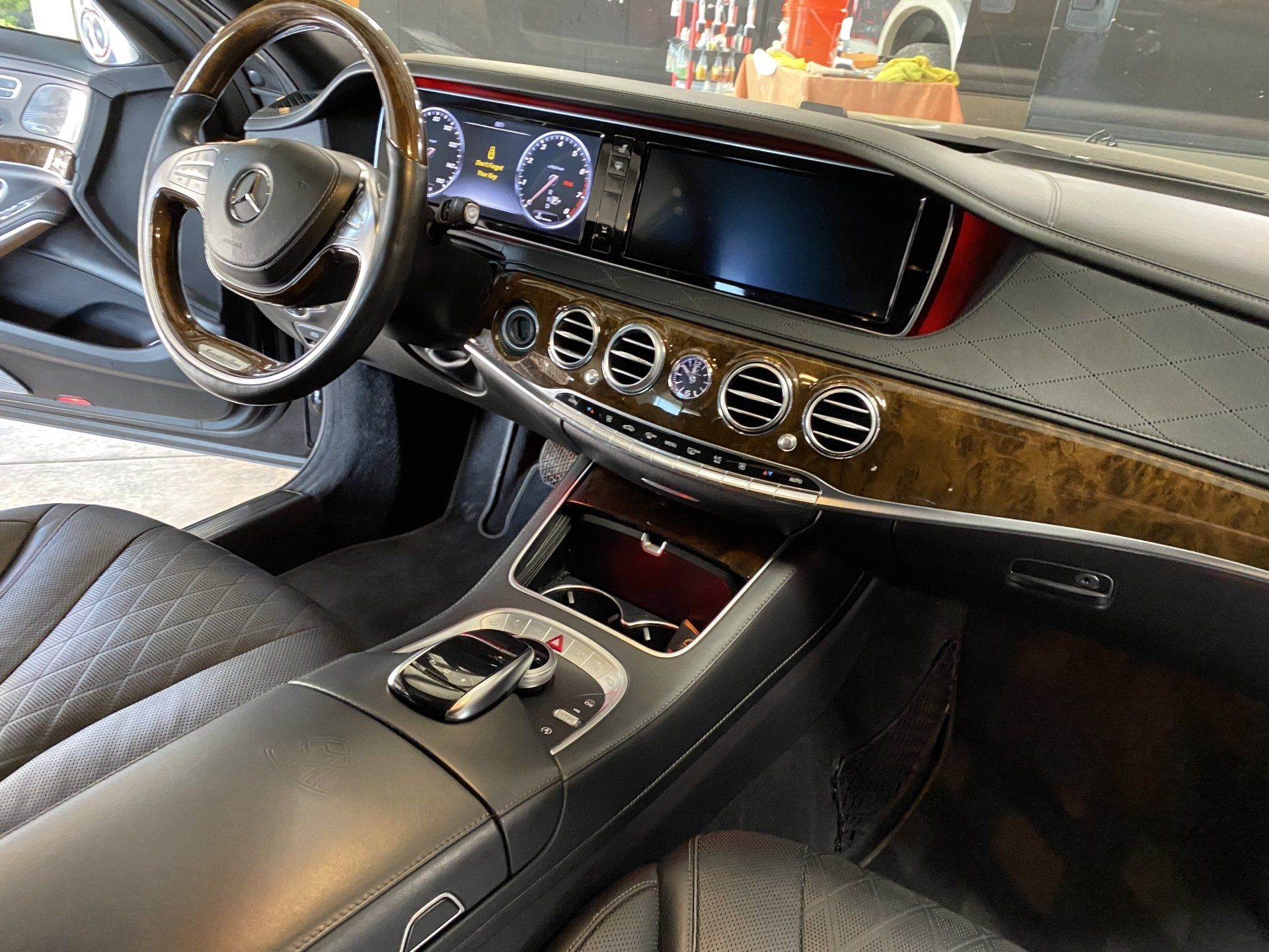 Luxury car interior with black leather seats, wood trim, steering wheel, digital dashboard, and center console