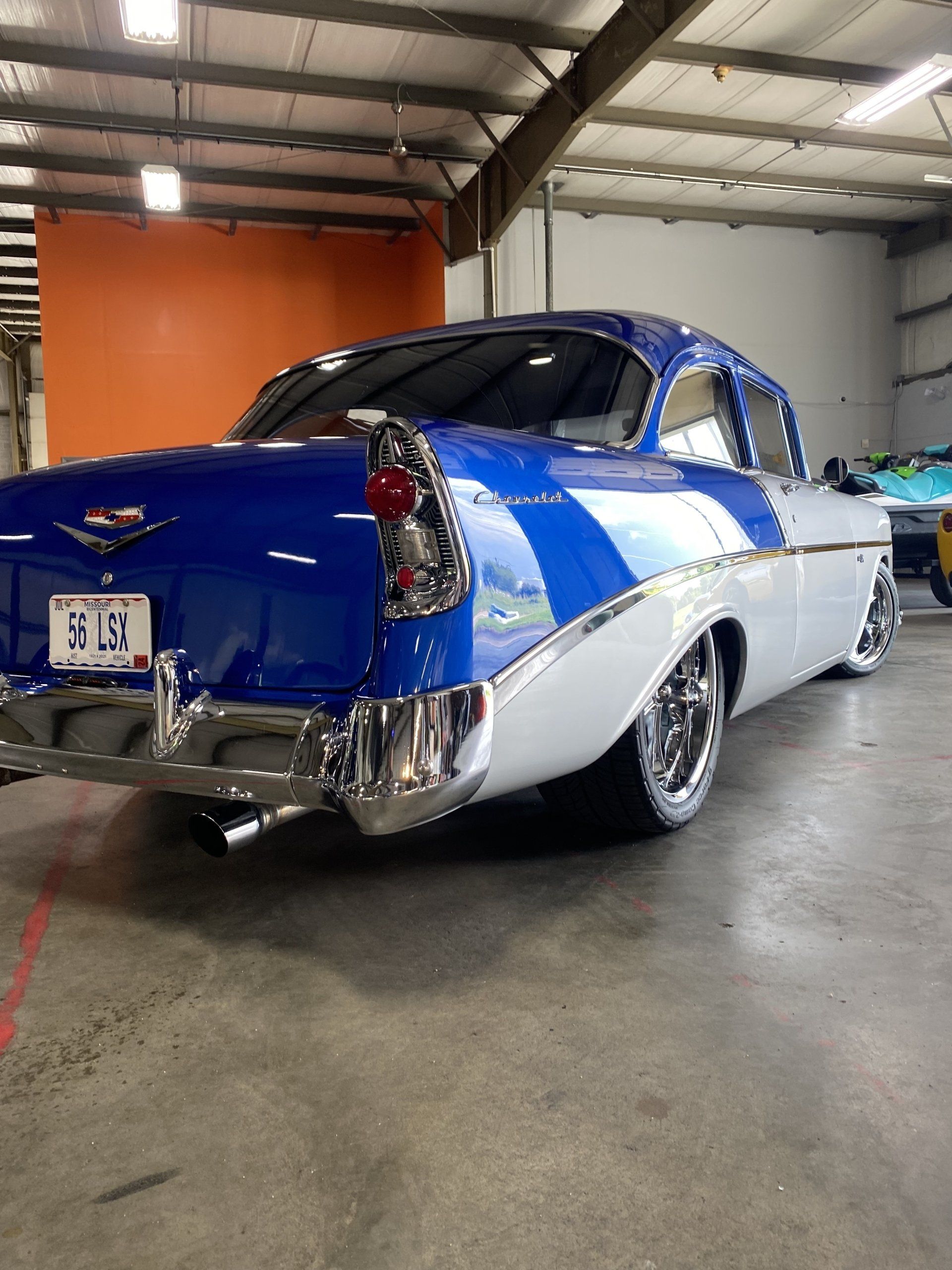 Blue and white classic car with chrome details parked indoors in a garage