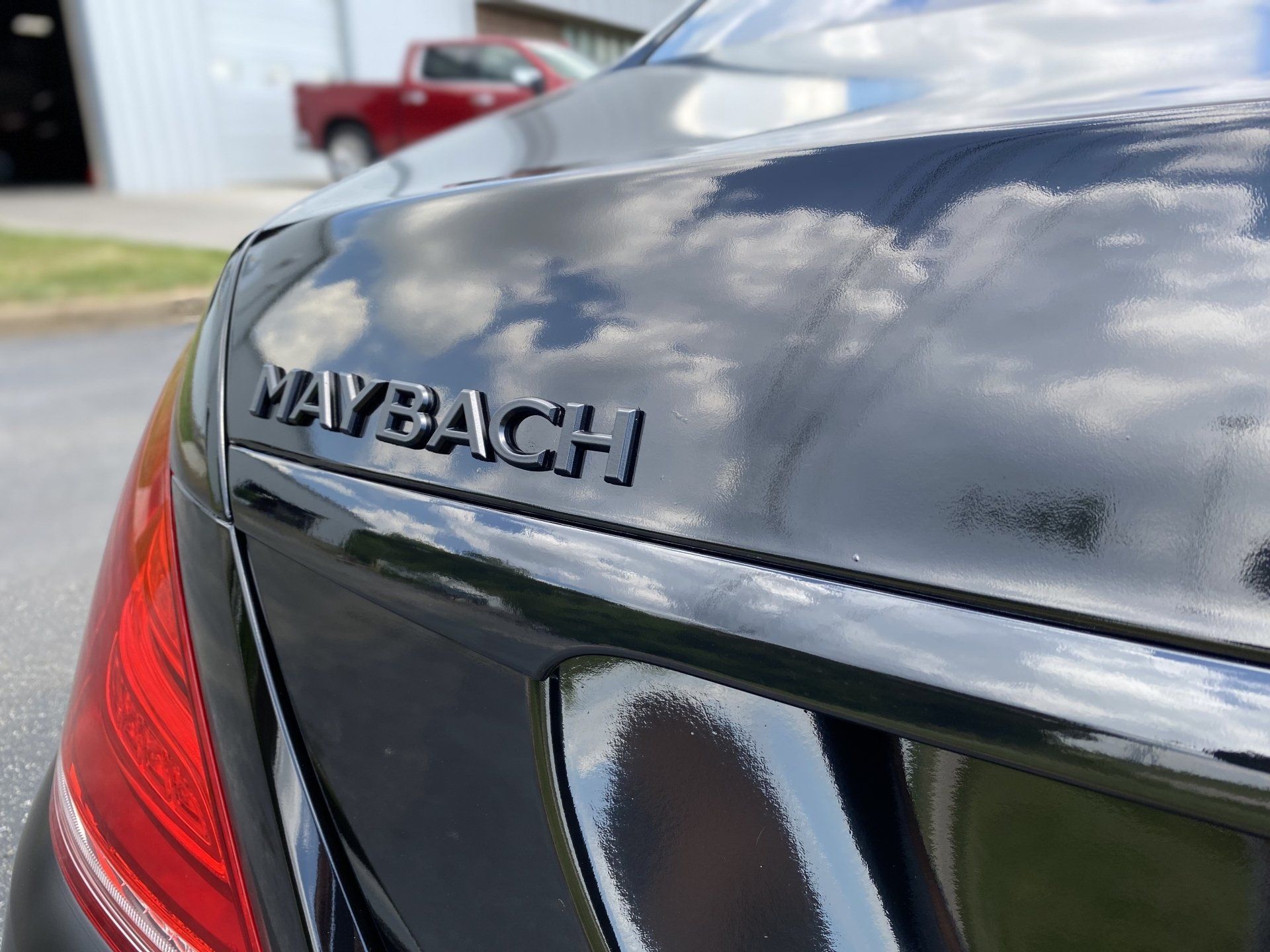 Close-up of a black Maybach car trunk with chrome badge and red taillight.