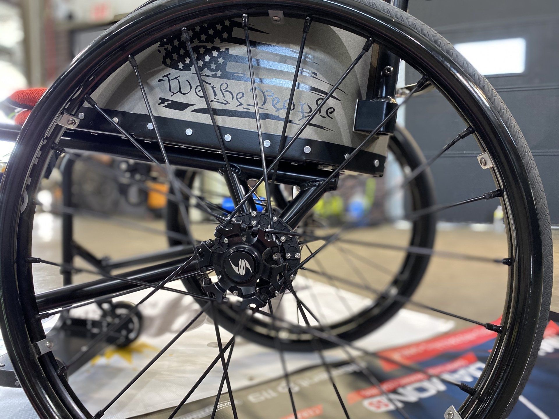 Black bicycle wheel with spokes and hub in a workshop or garage setting