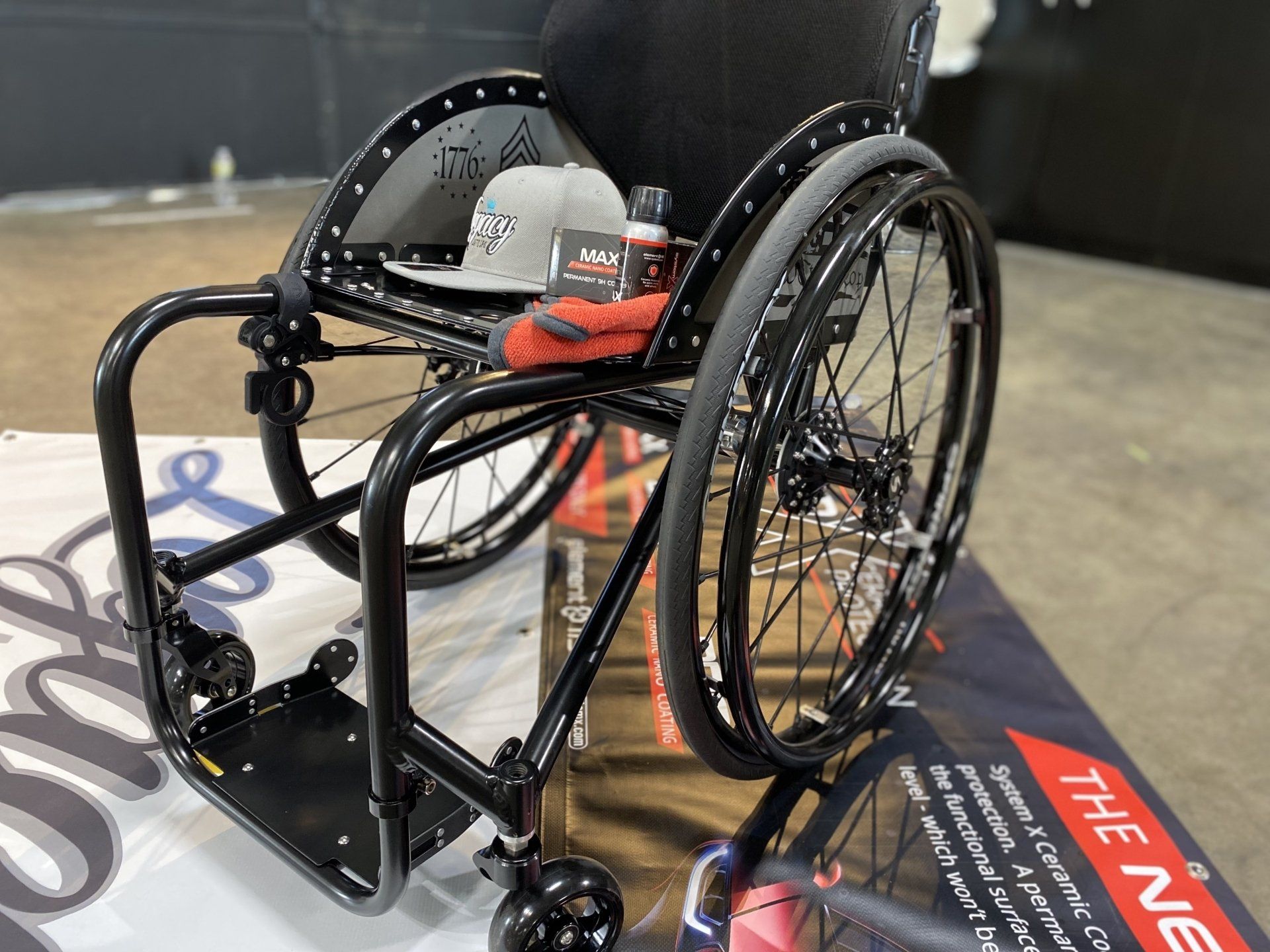 Wheelchair basketball chair with black frame and red wheels on a court logo.