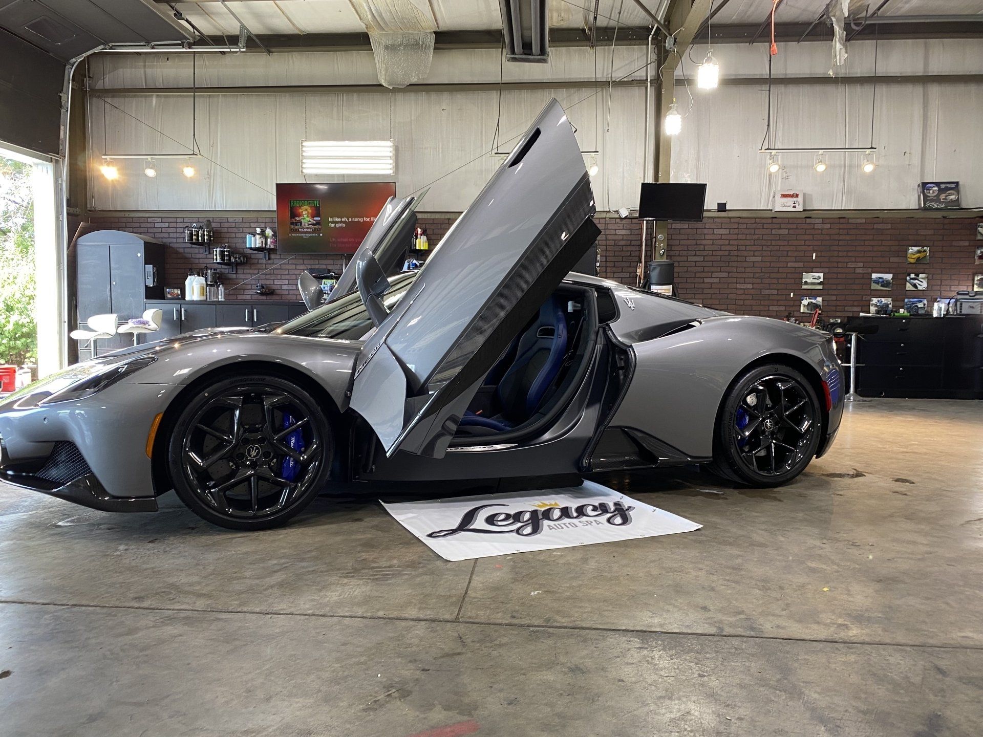 Silver sports car with scissor door open in an indoor garage showroom