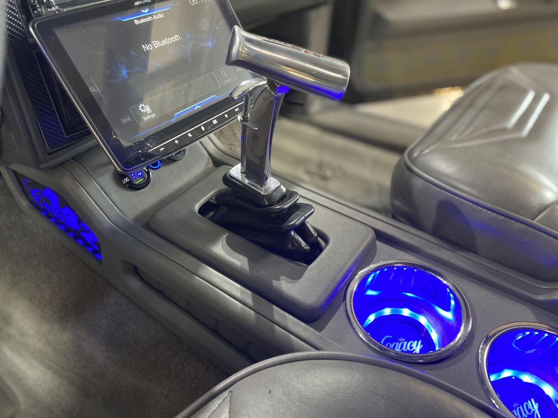 Custom car interior with glowing blue cup holders and a mounted gear shifter beside a touchscreen display