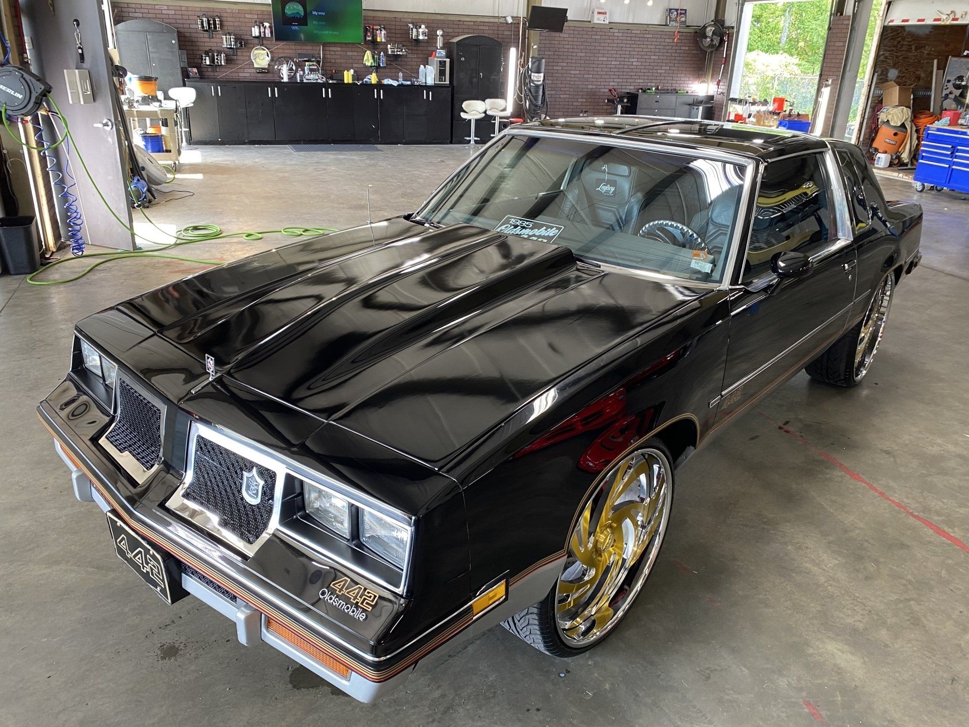 Black classic car with gold rims parked in a garage or workshop