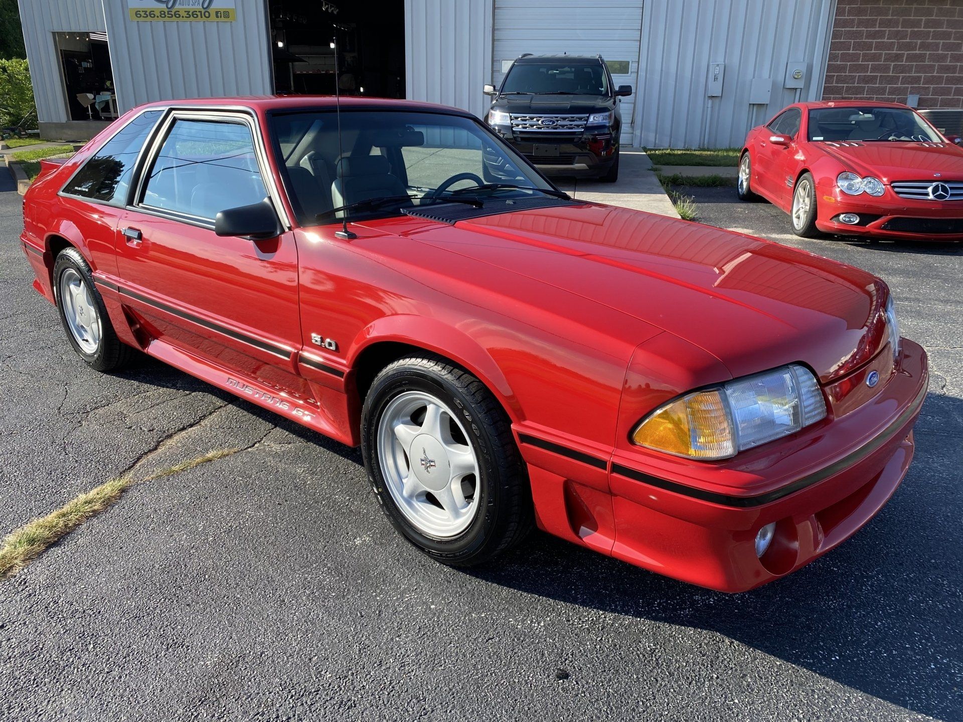 Red sports coupe parked outside an auto shop on a sunny day