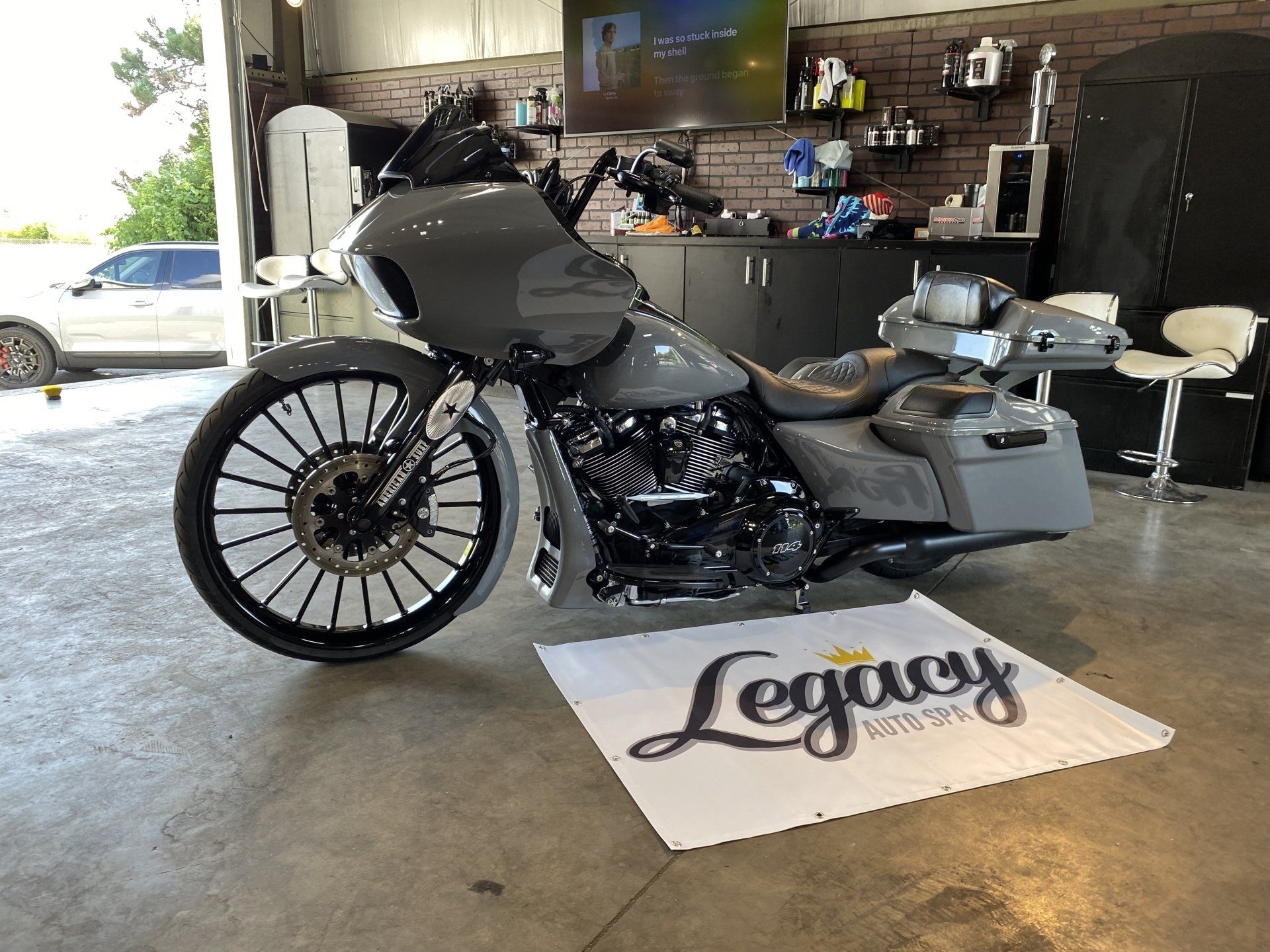 Custom gray touring motorcycle on a garage floor with a “Legacy” mat underneath.