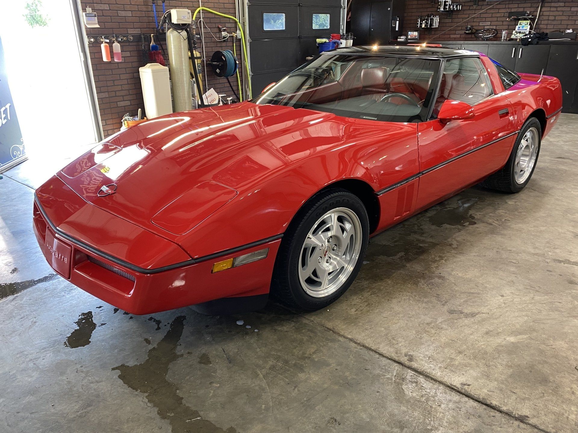 Red sports car parked in a garage, viewed from the front-left side.